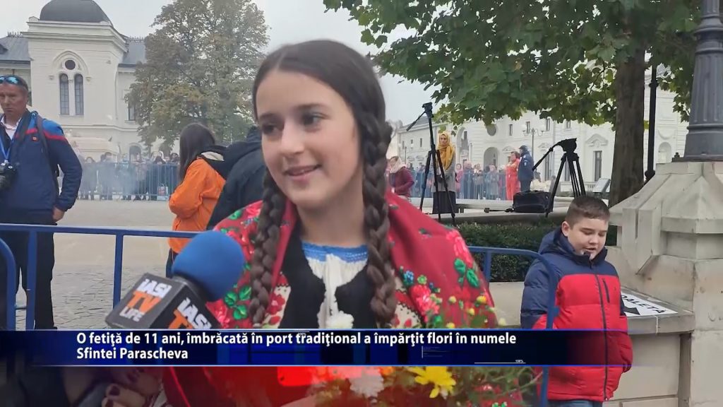 O fetitia de 11 ani, imbracata in port traditional a impartit flori in numele Sfintei Parascheva
