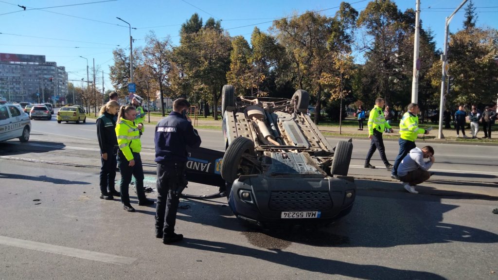 FOTO. O maşină a Jandarmiei s-a răsturnat în urma unui accident în faţa BCR din Podu Roş